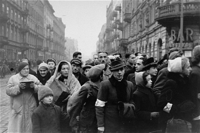 Jews are gathered at the intersection of Karmelicka and Nowolipki Streets in the Warsaw ghetto